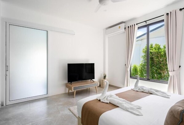 Une chambre d’hôtel moderne dotée d’un grand lit, d’un téléviseur à écran plat, d’une porte coulissante et d’une fenêtre avec des rideaux.