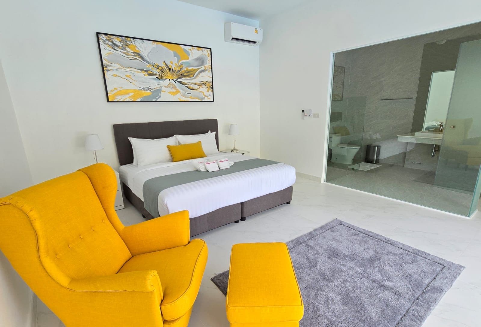 A modern bedroom with a bed, a sofa, and an ottoman.
