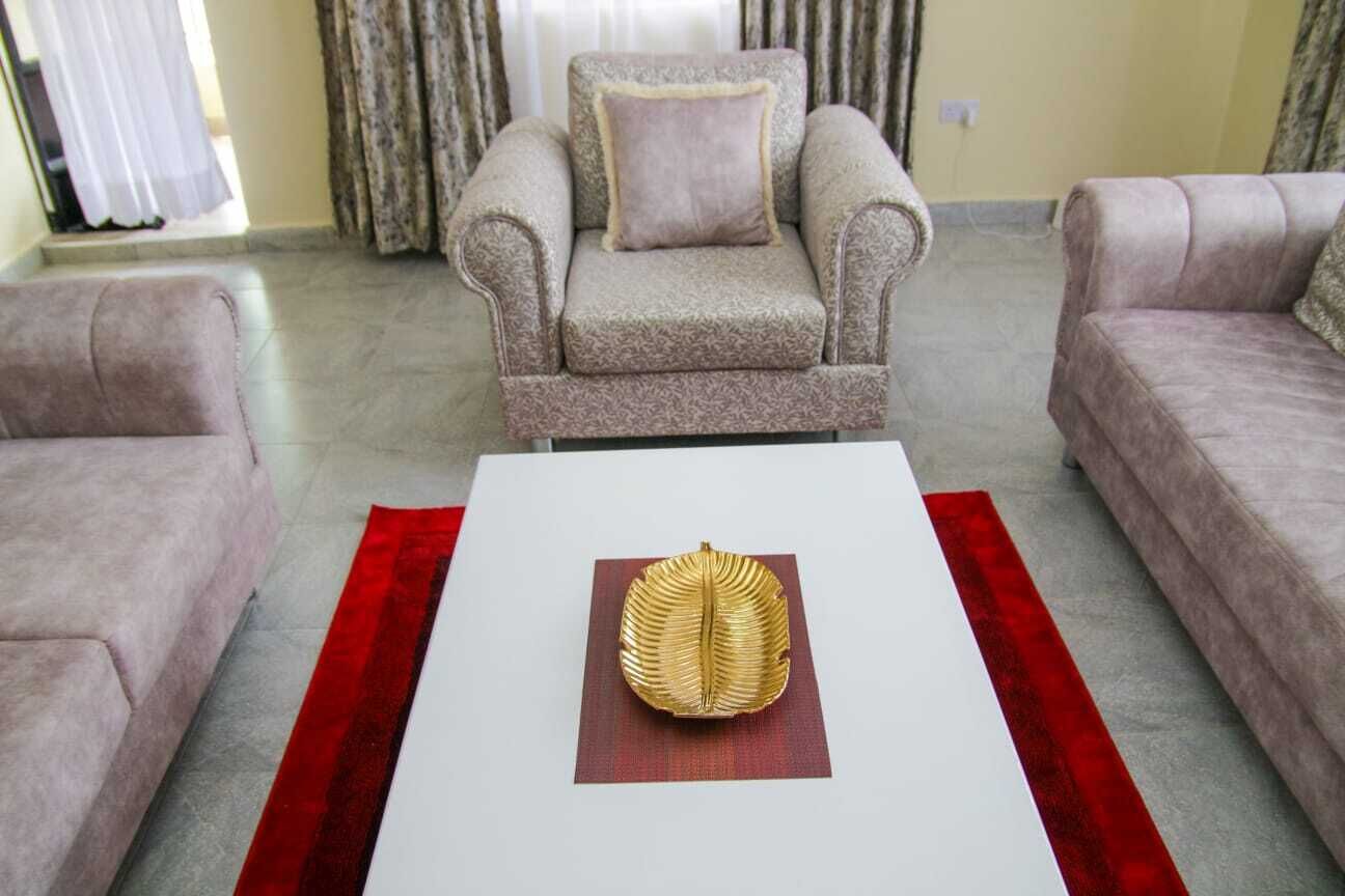 A living room with a beige armchair, a matching sofa, and a white coffee table with a decorative item.
