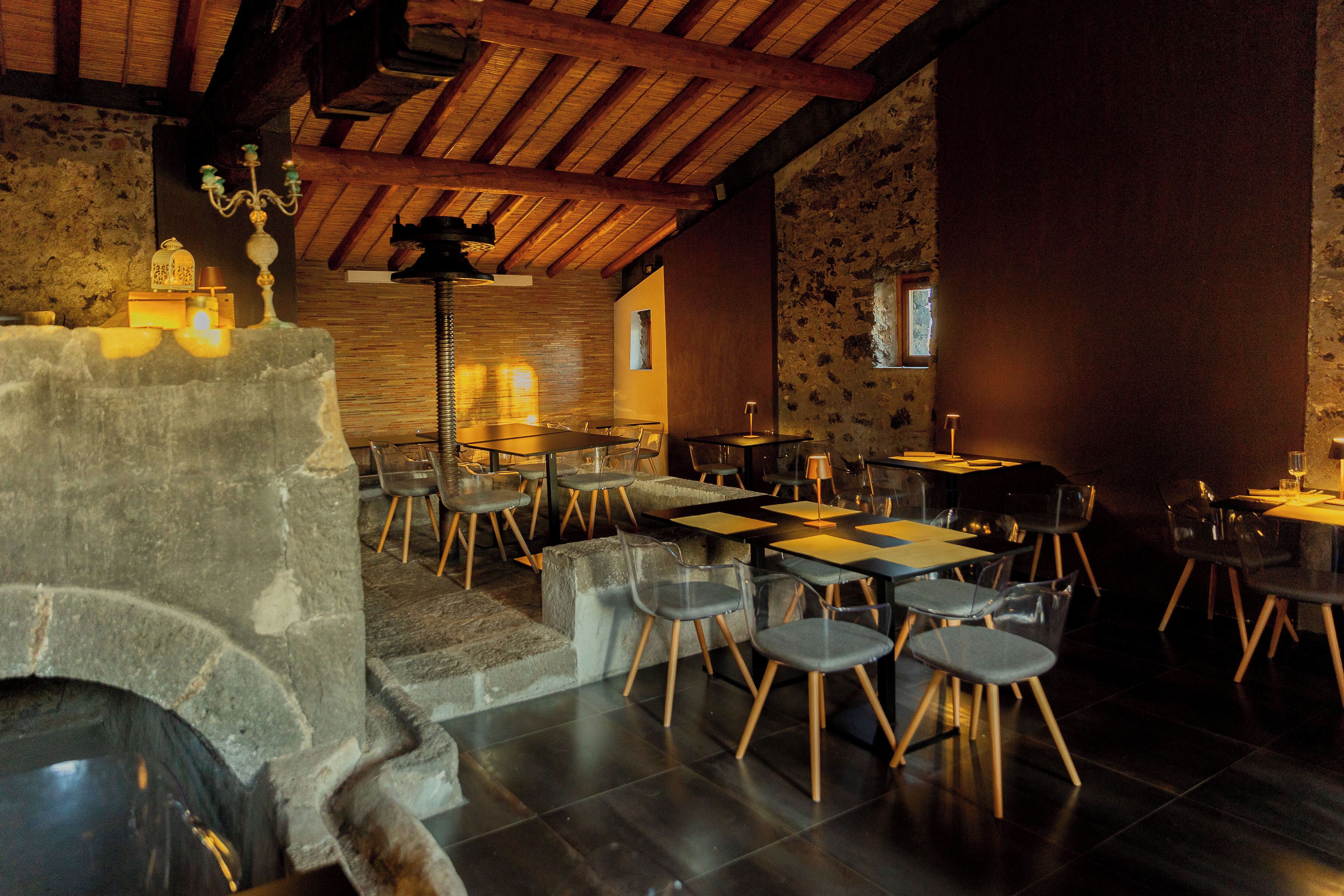 A restaurant with stone walls, wooden beams, and modern seating.