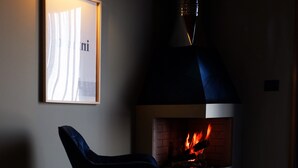 A modern living room with a fireplace, a framed picture on the wall, and a chair.