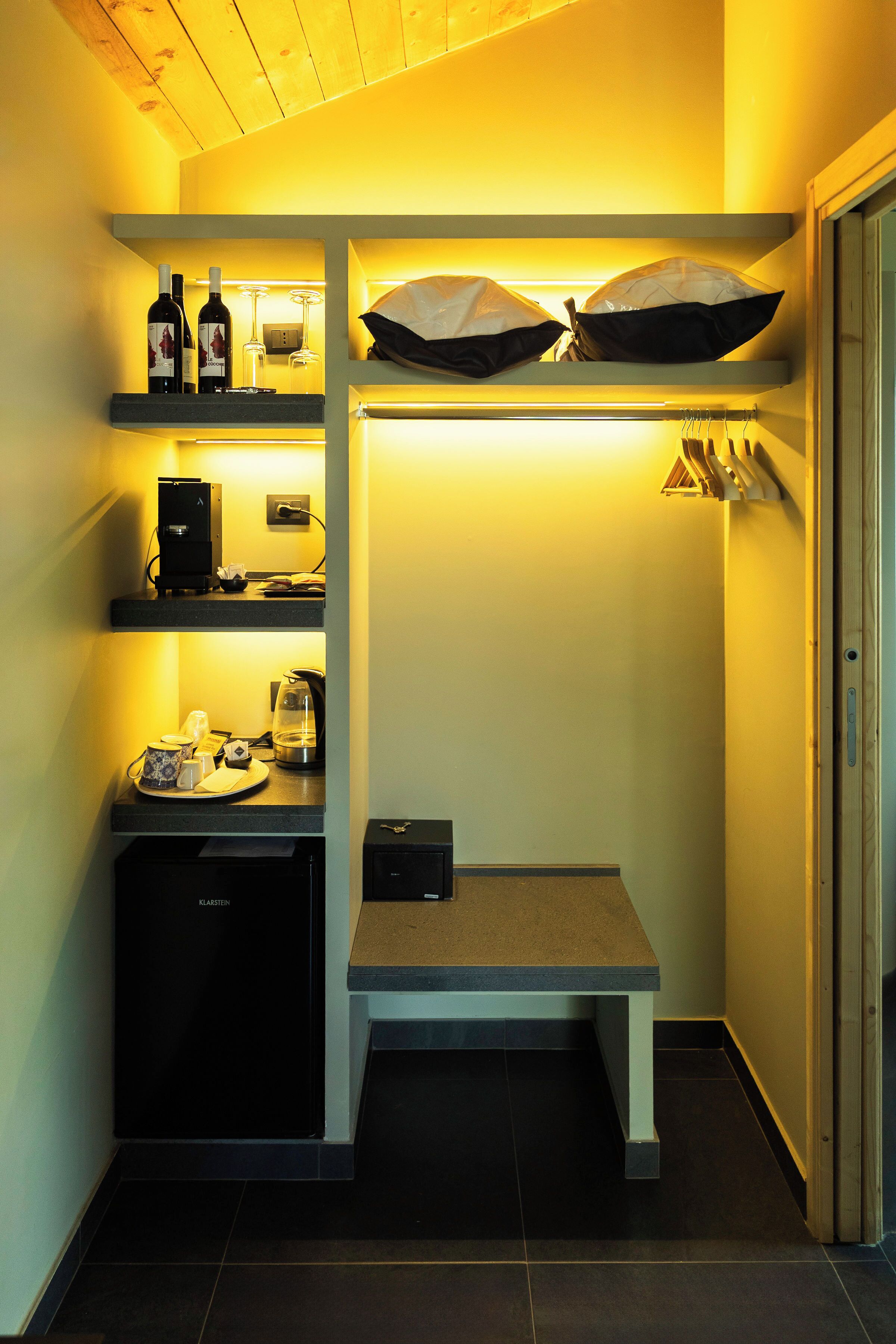 A compact kitchen with built-in appliances, a coffee machine, and storage shelves.