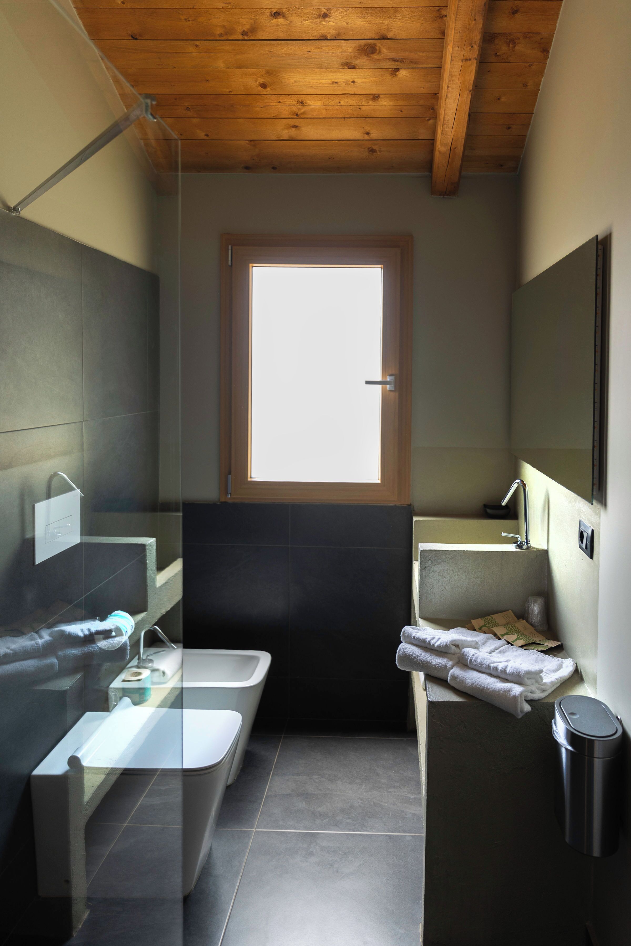 Un baño con ventana, bañera, lavamanos y cubo de basura.