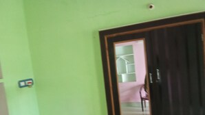 Ein Zimmer mit einer grünen Wand, einem gerahmten Spiegel und einer Tür.