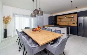 Eine moderne Küche mit einem Holztisch, grauen Polsterstühlen und Pendelleuchten.