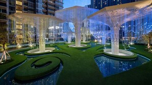Un espacio exterior moderno con juegos de agua geométricos y estructuras iluminadas.