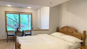A bedroom with a wooden bed, a desk with chairs, and a window with a view of trees. - Cozy bedroom close to C-train (Calgary)