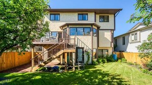 A two-story house with a wooden deck and a staircase leading to a balcony. - Cozy bedroom close to C-train (Calgary)