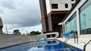 A swimming pool with a tiled edge, metal handrails, and a drainage grate in the foreground. - Lux Suites Siaya Park Apartments (Nairobi)