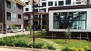 A modern building with a large window, a well-maintained garden, and a paved walkway. - Lux Suites Siaya Park Apartments (Nairobi)