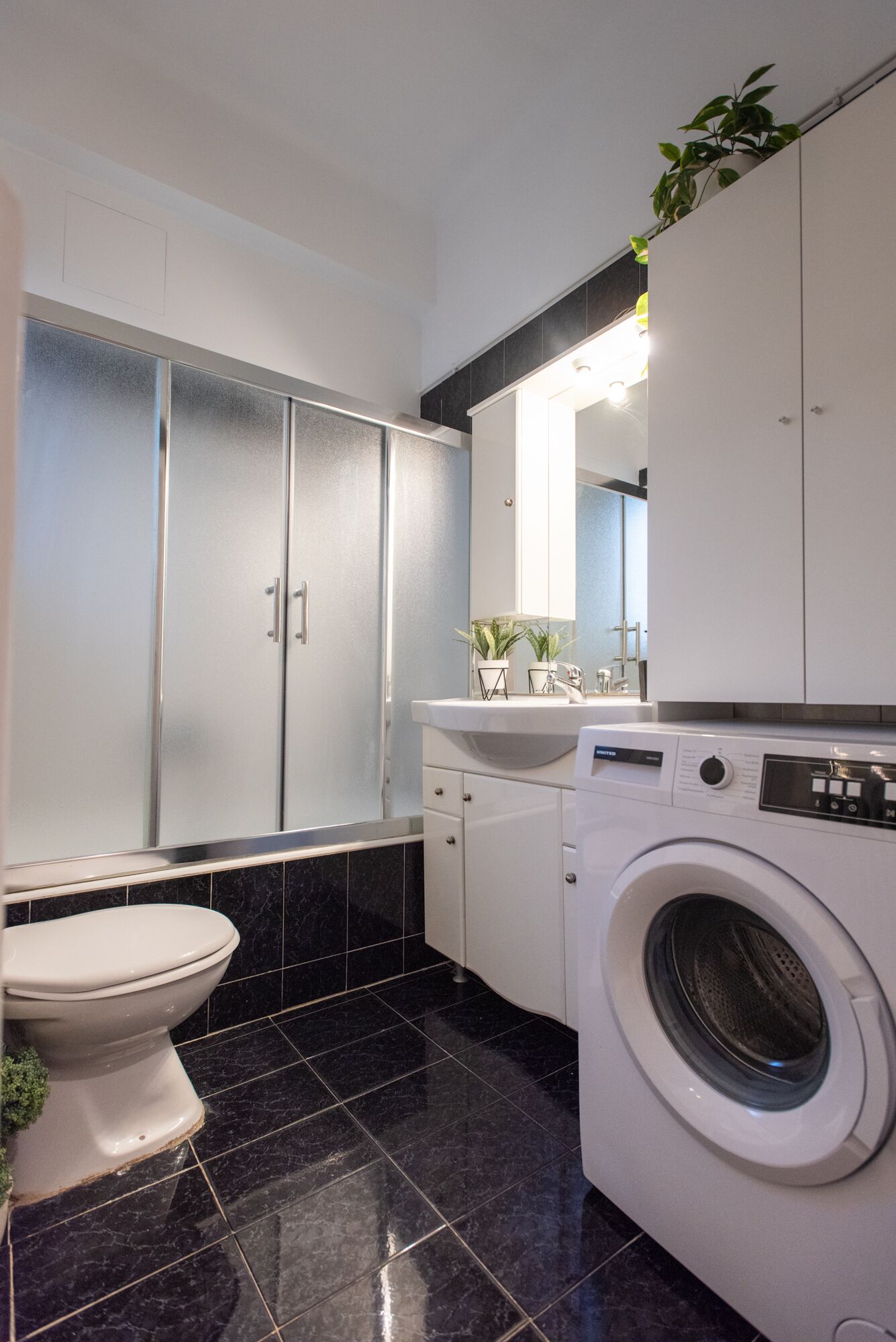 A modern bathroom with a toilet, a washing machine, and a sink.
