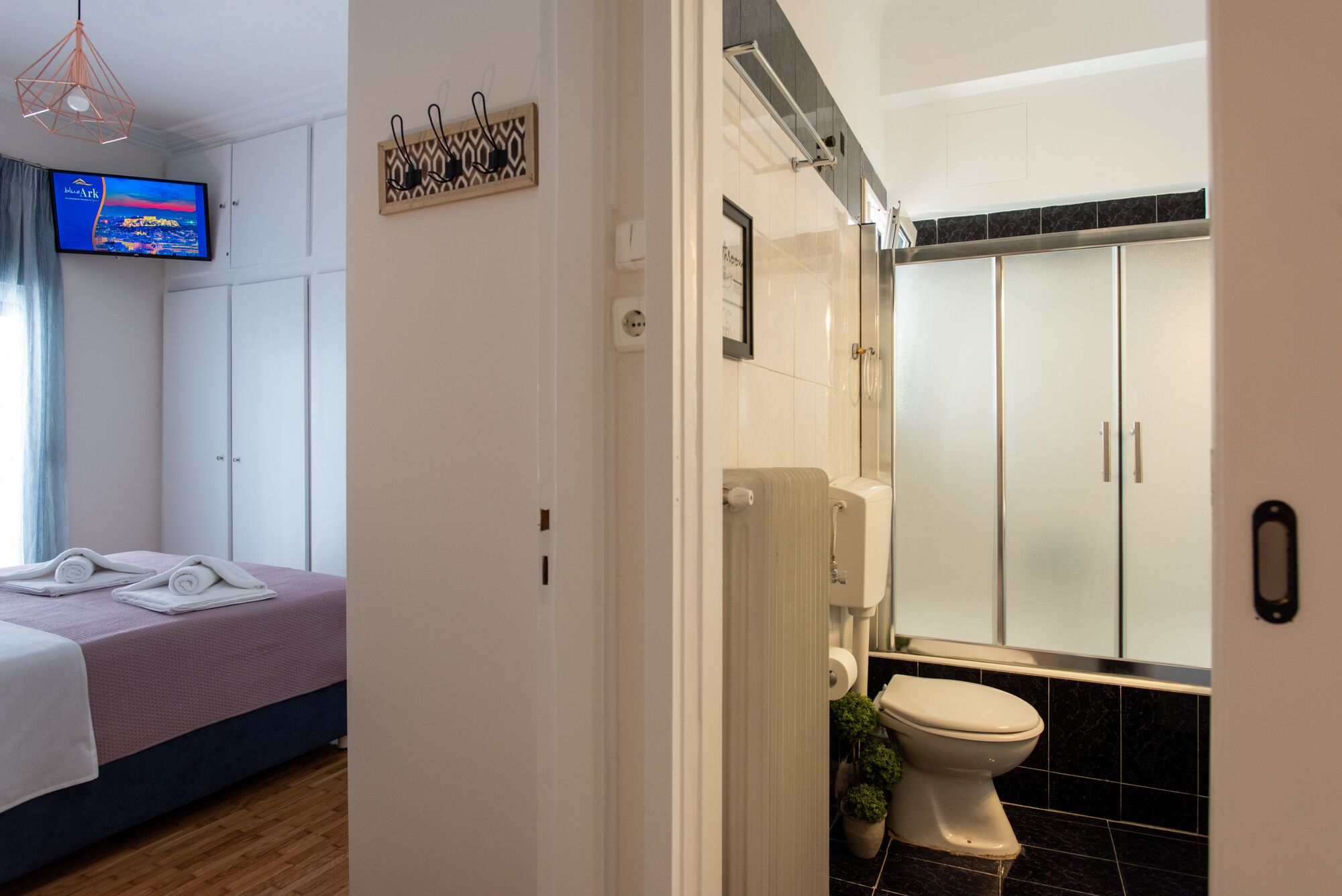 A hotel room with a bed, a television, a bathroom with a toilet and cabinets.