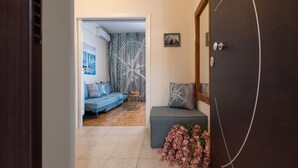 A hallway leading to a living area with a sofa, a small table with drinks, and a decorative plant.