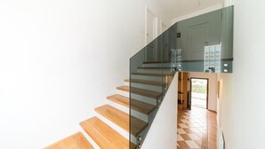 Eine moderne Treppe mit Glasgeländern und Holzboden, die zu einer zweiten Etage führt.