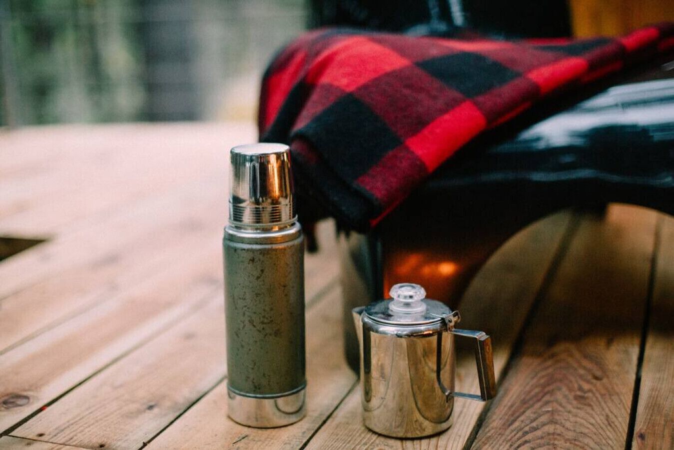 Eine Metall-Thermoskanne und ein Metall-Kaffeekännchen auf einer Holztisch.
