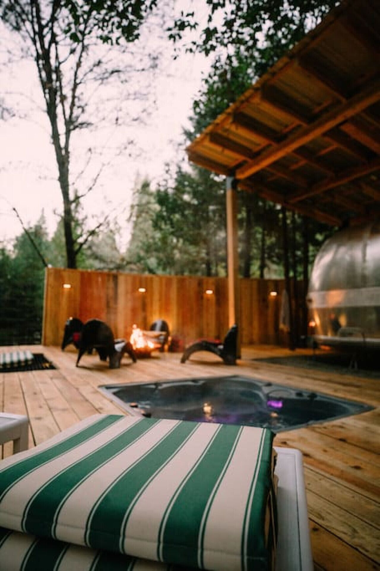 An outdoor patio with a hot tub, wooden deck, and a covered seating area.