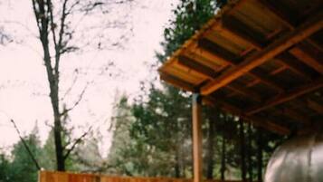 An outdoor patio with a hot tub, wooden deck, and a covered seating area.