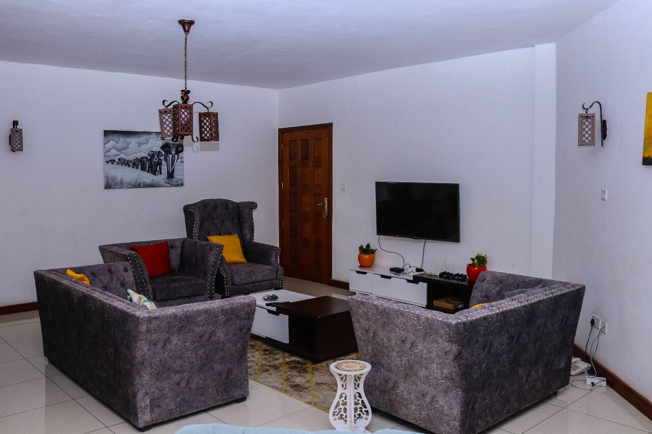 Ein Wohnzimmer mit einer Sofagarnitur, einem Couchtisch, einem Fernseher und Dekoration.