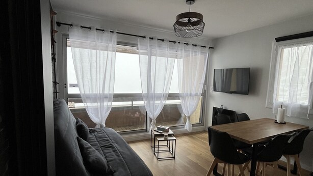 Una sala de estar moderna con sofá, mesa de comedor, sillas y televisor.