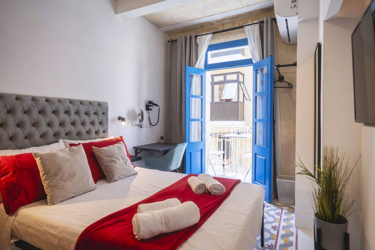 Une chambre d’hôtel avec un grand lit, un bureau et une vue sur le balcon extérieur.