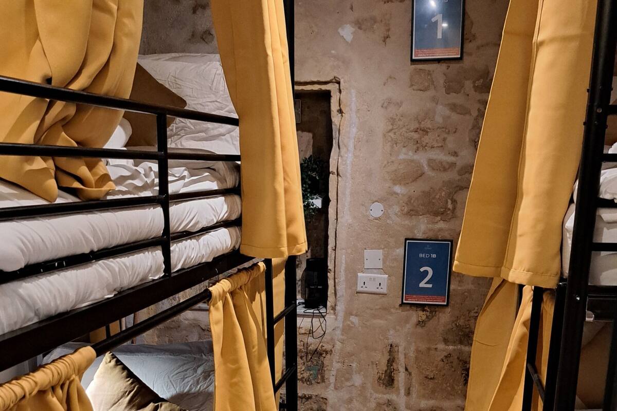Une pièce avec des lits superposés, un sol à motifs et un mur en pierre.