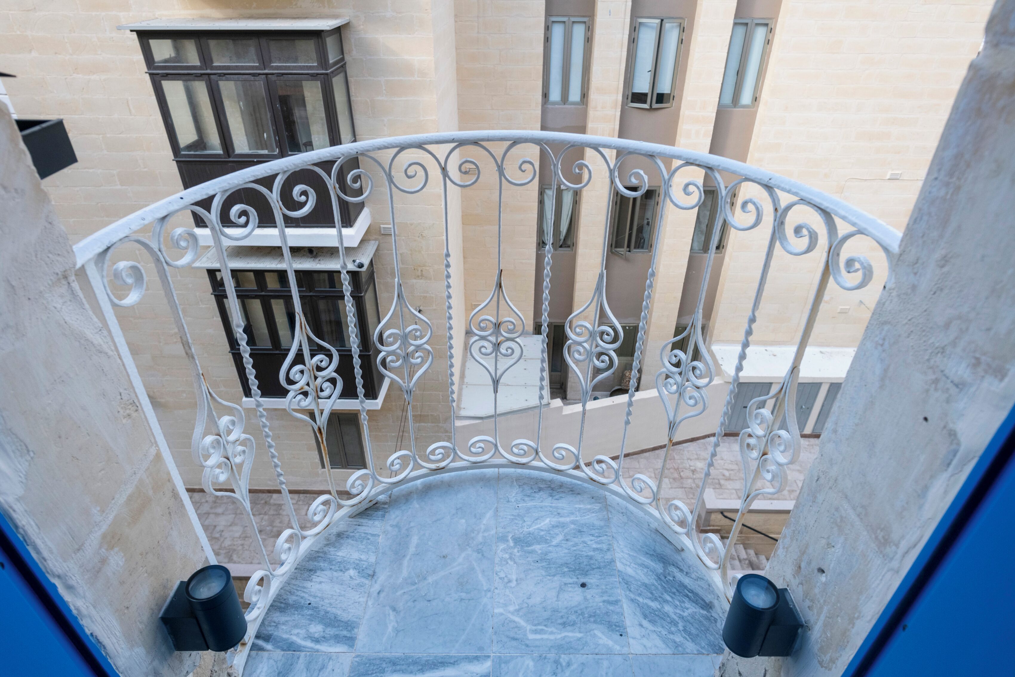 A balcony with white wrought iron railings and a tiled floor.