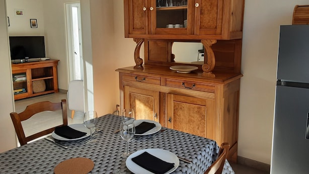 Ein Essbereich mit einem Holzkabinett über einem Tisch, einem Fernseher in der Ecke und einem Kühlschrank zur Rechten.