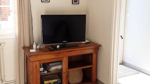 Ein Wohnzimmer mit einer Holzunterhaltungsecke, einem Flachbildfernseher und einer Tür, die auf einen Balkon führt.