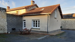 Ein kleines Haus mit Ziegeldach, Steinmauer und einem Schotterweg.