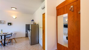 A compact kitchen with a dining area, a refrigerator, and a wooden door. - Cozy apartment in Klek with swimming pool (Klek)