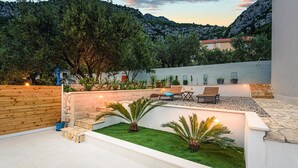 A modern outdoor patio with a seating area, a small garden, and a view of the surrounding hills. - Cozy apartment in Klek with swimming pool (Klek)