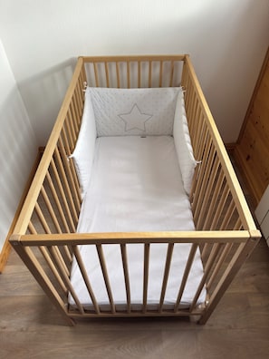 A wooden crib with a white mattress and a star-shaped pillow.