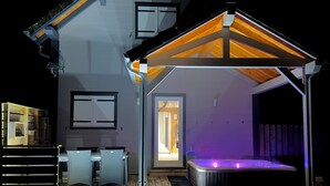 A two-story house with a covered patio area featuring a hot tub and outdoor seating. - Climontaine Chalet with Jacuzzi - Vosges Mountains (Colroy-la-Roche)