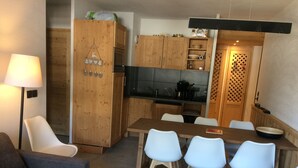 En kompakt opholdsstue med spiseplads, tekøkken og sofa.