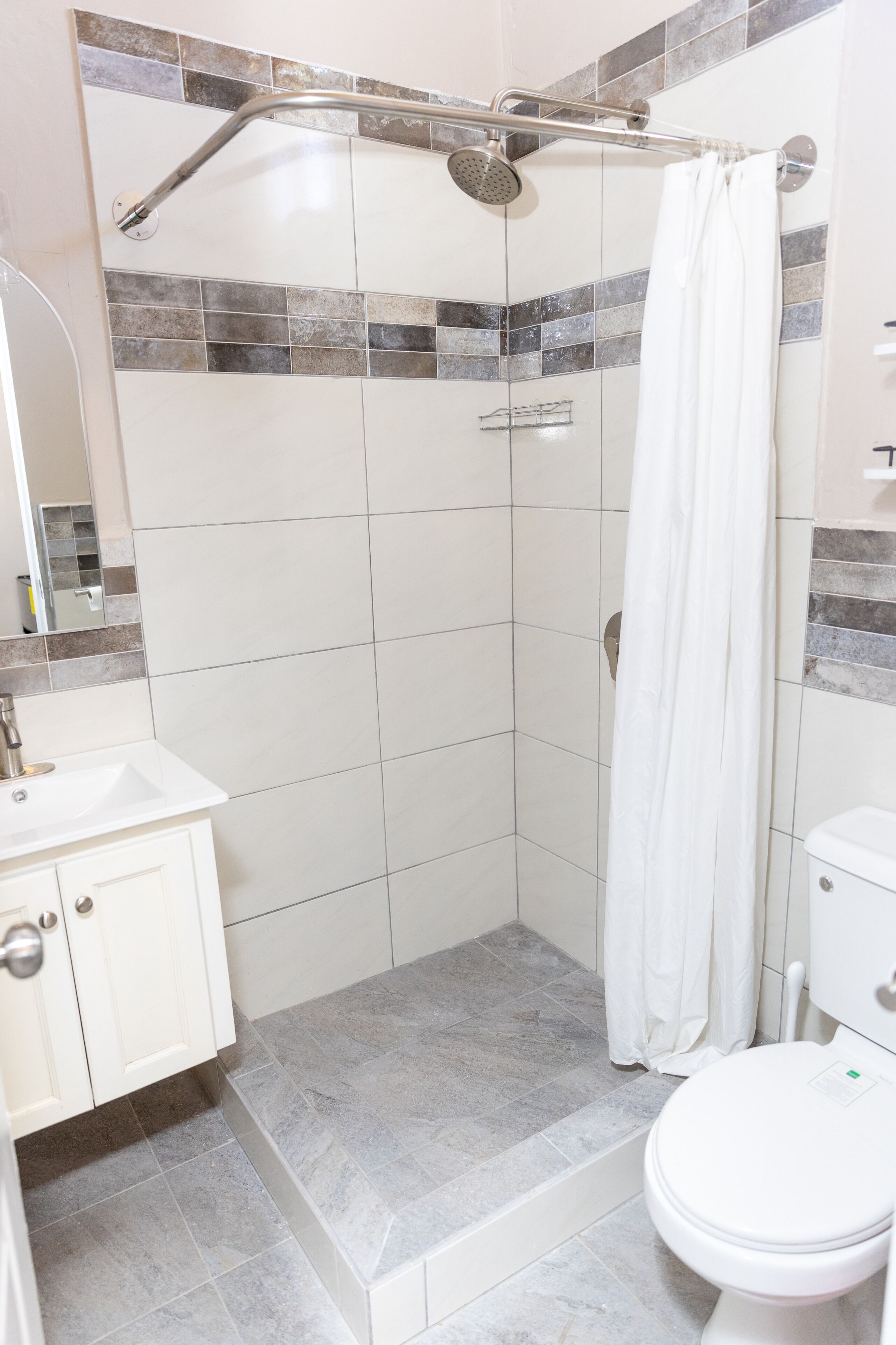Een badkamer met douche, toilet en wastafel.