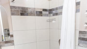 Een badkamer met douche, toilet en wastafel.