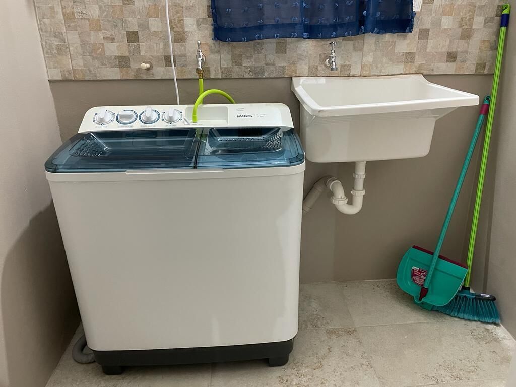 Eine kleine Waschmaschine und ein Waschbecken in einem Badezimmer.