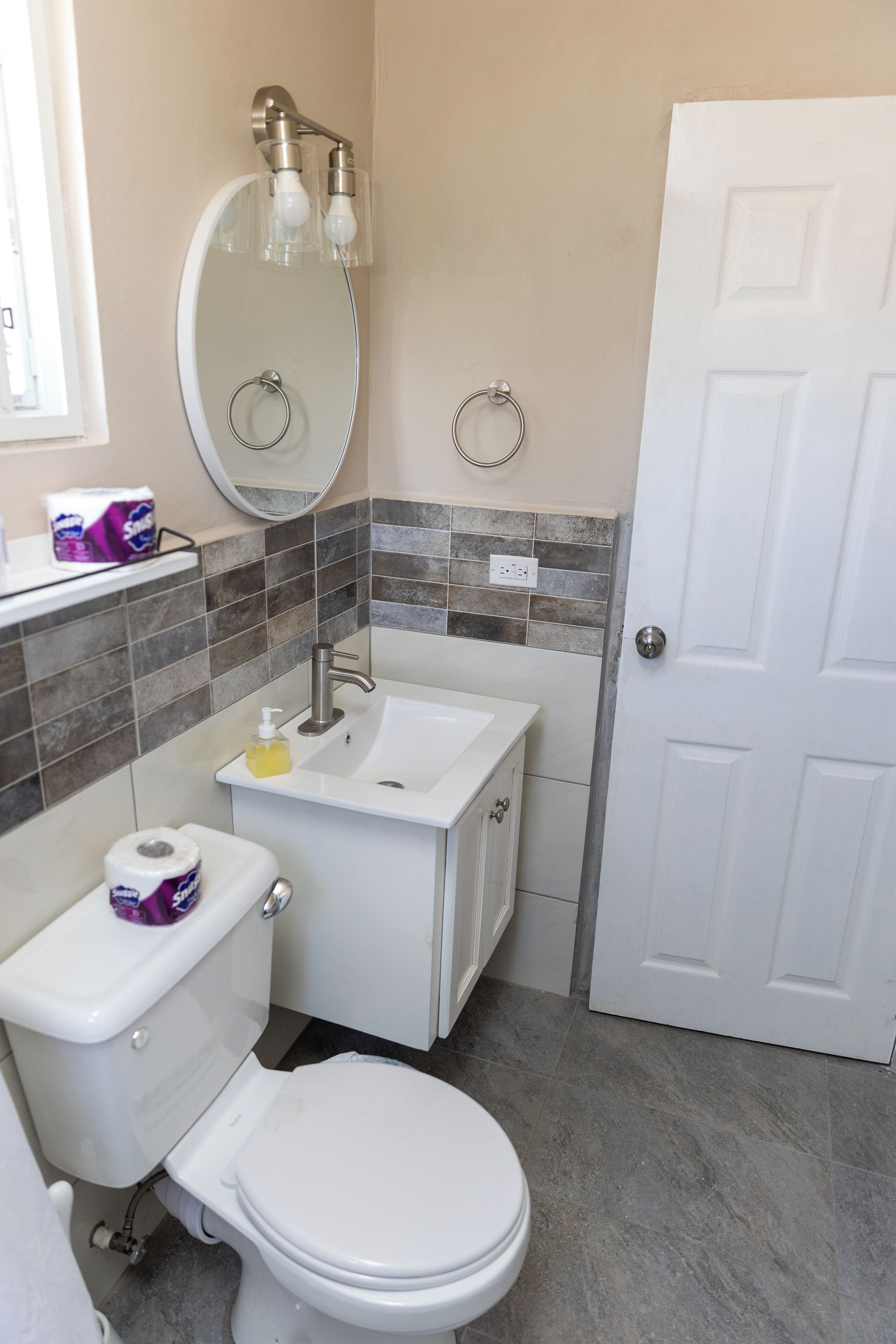 Une salle de bain comprenant des toilettes, un lavabo, un miroir et une porte.