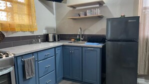 Une cuisine avec des armoires bleues, un réfrigérateur noir, un four à micro-ondes et un évier.
