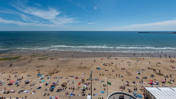A beach with people sunbathing and swimming, a pier in the distance, and a clear blue sky. - 3* Apartment facing the beach with balcony and equipped kitchen (Les Sables-d'Olonne)