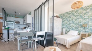 A modern, compact hotel room with a kitchenette, a dining area, a bed, and a small seating area. - 3* Apartment facing the beach with balcony and equipped kitchen (Les Sables-d'Olonne)