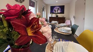 A dining area with a table set for four, surrounded by chairs, and a large decorative wall piece above the table. - Cozy lodge with SPA, pets allowed and parking (Saint-Léon)