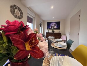Comedor con una mesa dispuesta para cuatro personas, sillas alrededor y una gran pieza decorativa sobre la mesa.