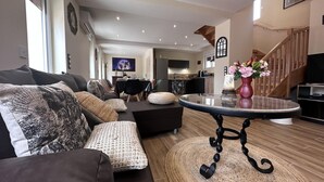 A modern living room with a sofa, a coffee table, and a dining area in the background. - Cozy lodge with SPA, pets allowed and parking (Saint-Léon)