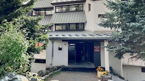 A modern building with a metal roof, large windows, and a sign in French.