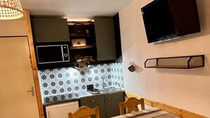 A compact kitchen with a microwave, sink, and wooden cabinets.