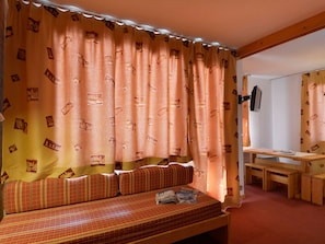 Um quarto acolhedor com uma cama, um banco de madeira e uma mesa.