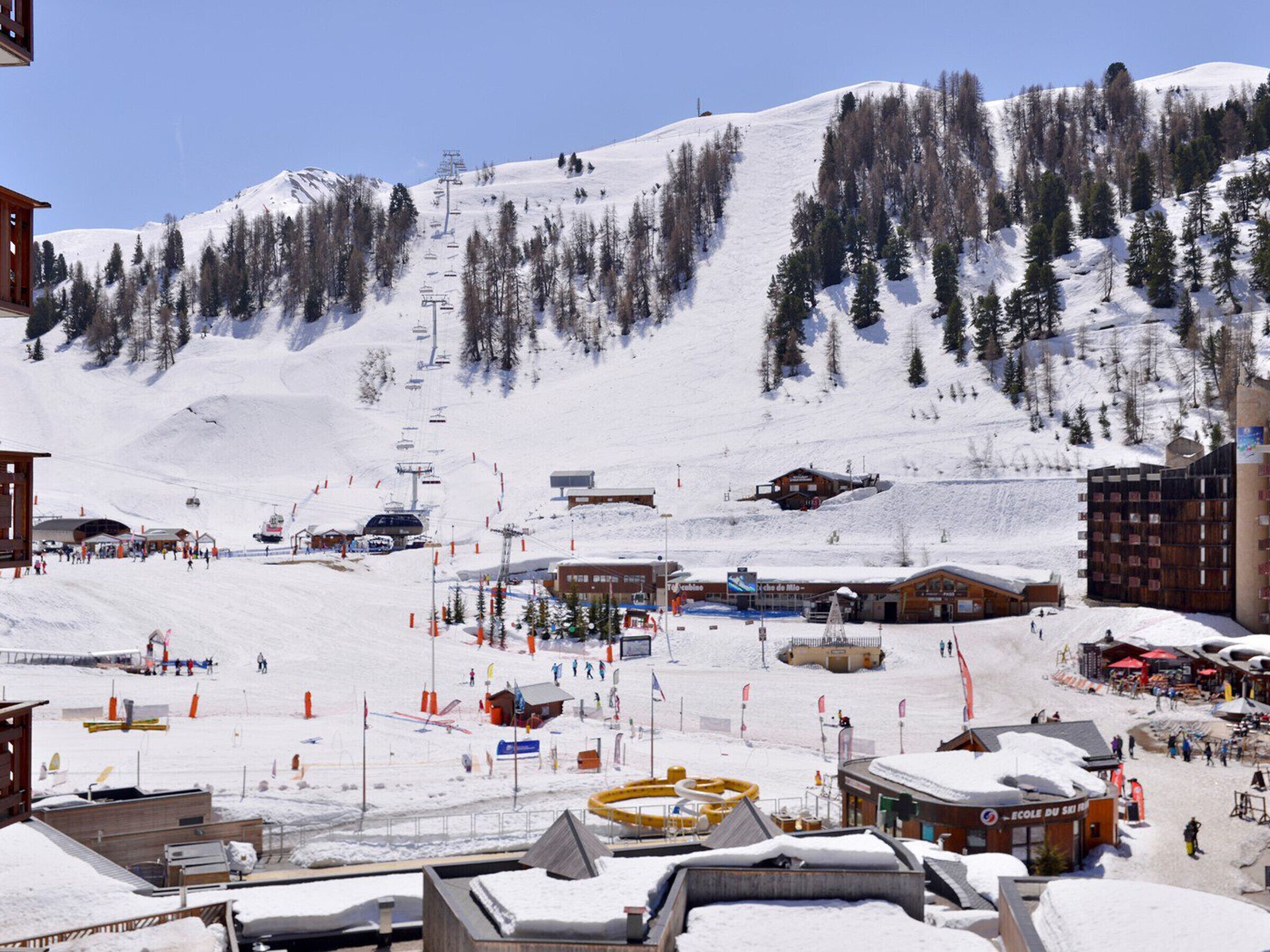 A ski resort with a ski lift, buildings, and a snowy landscape.