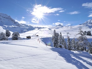 Paisagem de montanhas cobertas de neve, com teleféricos e céu claro.