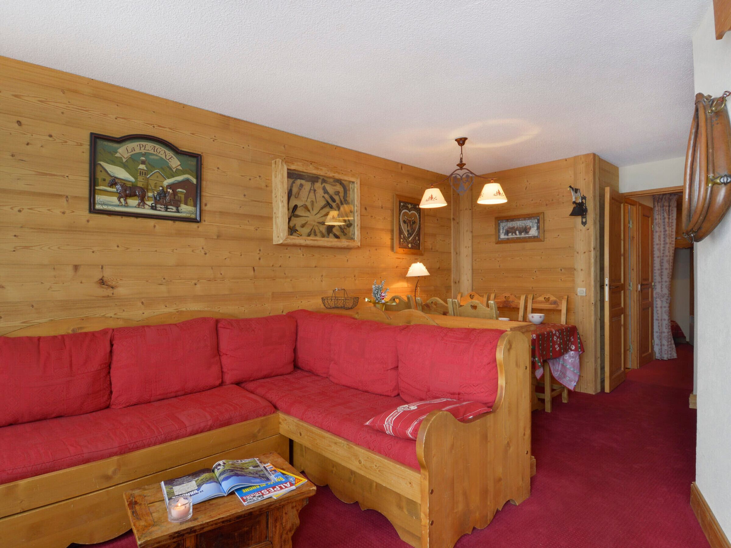 Un interior acogedor de madera, con un sofá rojo, una mesa de comedor de madera y una araña.